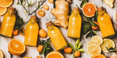 Bottles of orange juice, orange slices, ginger, laid out on a table.