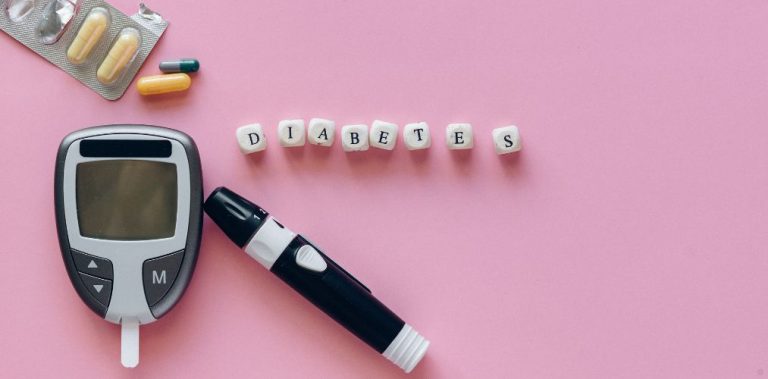 Diabetes medication and blood glucose test on a pink background.