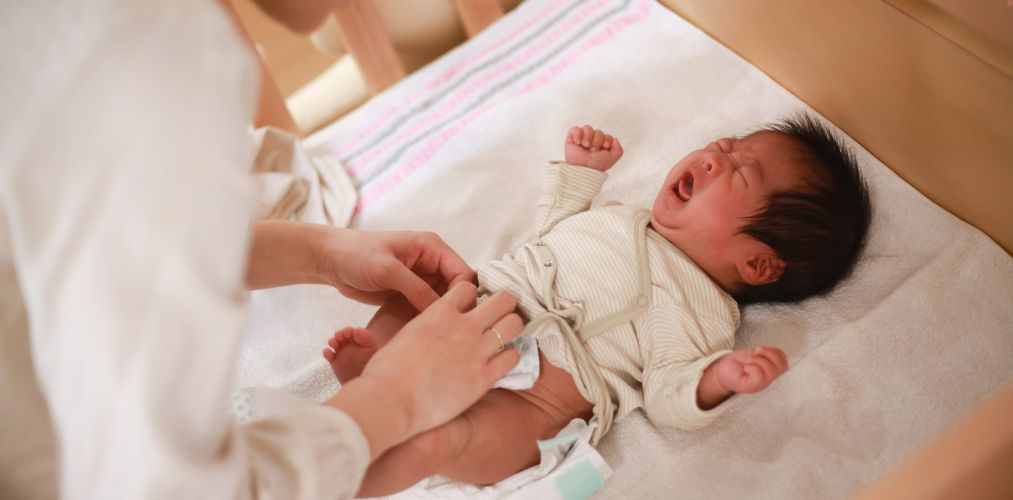 A baby crying while their parent changes their diaper.